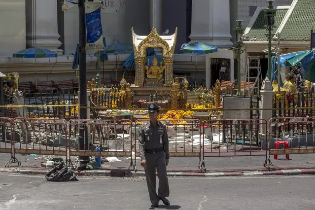 A police officer stands in front of the Erawan shrine, the site of a deadly blast, in central Bangkok, Thailand, August 18, 2015. Thai authorities said on Tuesday they were looking for a suspect seen on closed-circuit television (CCTV) footage near the renowned shrine where a bomb blast killed 22 people, including nine foreigners from several Asian countries. (Photo by Athit Perawongmetha/Reuters)