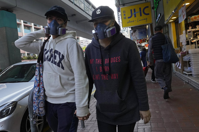 A couple wearing face masks walk at a street in Hong Kong Monday, February 17, 2020. COVID-19 viral illness has sickened tens of thousands of people in China since December. (Photo by Vincent Yu/AP Photo)