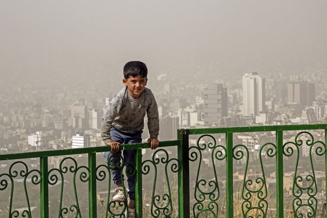 A boy plays outside during a heavy sandstorm in the north of Iran's capital Tehran on May 17, 2022. Government offices, as well as schools and universities were announced closed in many provinces in Iran due to “unhealthy weather” conditions and sandstorms, state media reported. (Photo by AFP Photo/Stringer)