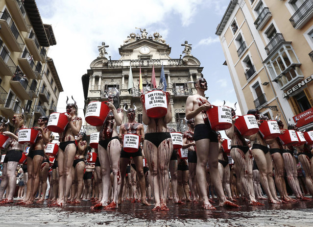 Animal rights activists holds buckets with a slogan reading: “San Fermin is Blood bath” during a protest on the City Hall Square in Pamplona, nothern Spain, 05 July 2016, on the eve of the beginning of the traditional f Sanfermines festival. The action was organized by the animal rights organization PeTA (People for the ethical Treatment of Animals) and “Anima Naturalis” to protest against the cruelty against bulls during the annual Sanfermines festival. (Photo by Jesus Diges/EPA)