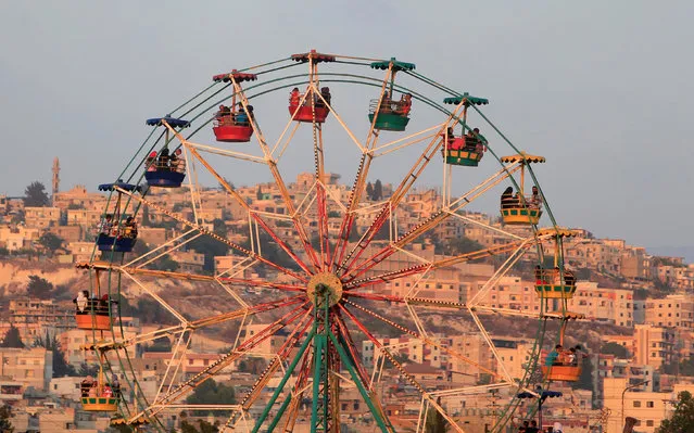 People ride a Ferris wheel in an amusement park as they celebrate the  first day of the Muslim holiday of Eid al-Fitr, which marks the end of the holy month of Ramadan at the port-city of Sidon, southern Lebanon, July 6, 2016. (Photo by Ali Hashisho/Reuters)