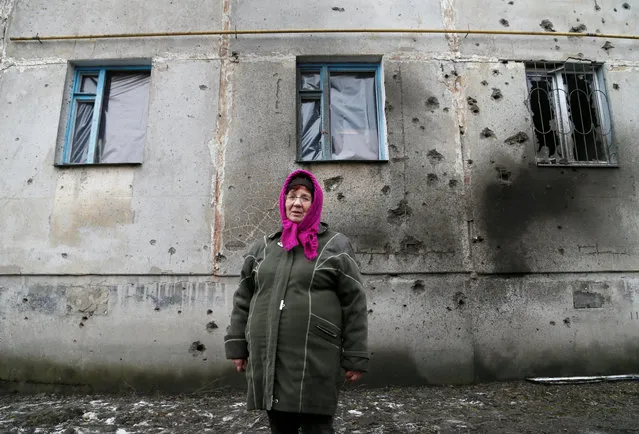 Local resident Larisa Beletskaya, 70, stands in front of an apartment block damaged during recent fighting between the armed forces of Ukraine and the separatist Lugansk People's Republic in the settlement of Holubivske in Luhansk region, Ukraine on February 19, 2020. (Photo by Alexander Ermochenko/Reuters)