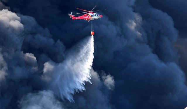 A firefighting helicopter extinguishes a fire at a factory in Incheon, South Korea, 20 October 2024. (Photo by Yonhap/EPA/EFE)