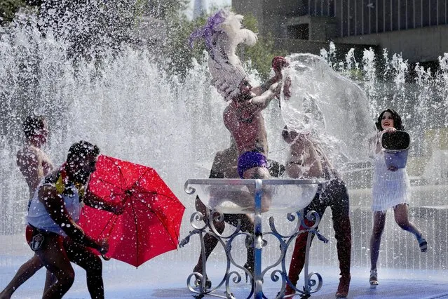 Members of the Australian cabaret and Circus troupe cool down in a fountain on the Southbank in London, Tuesday, July 19, 2022. Britain shattered its record for highest temperature ever registered Tuesday, with a provisional reading of 39.1 degrees Celsius (102.4 degrees Fahrenheit), according to the country's weather office – and the heat was only expected to rise. (Photo by Frank Augstein/AP Photo)
