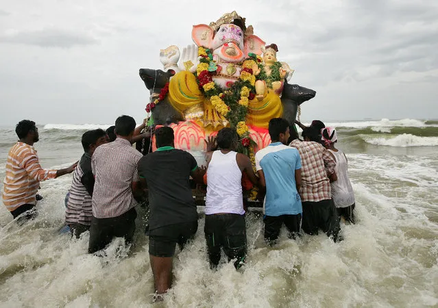 Devotees carry an idol of the Hindu god Ganesh, the deity of prosperity, into the Bay of Bengal for its immersion during the ten-day-long Ganesh Chaturthi festival in Chennai, India, August 27, 2017. (Photo by P. Ravikumar/Reuters)