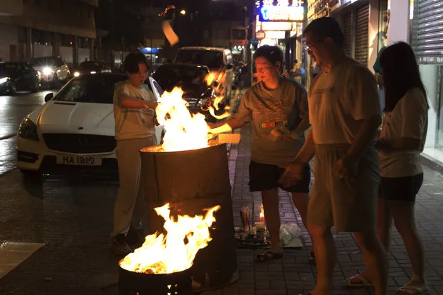 In this August 31, 2017, photo, a family burns paper money – locally known as “Hell Money” – during the “Hungry Ghost Festival” on a street in Hong Kong. (Photo by Kin Cheung/AP Photo)