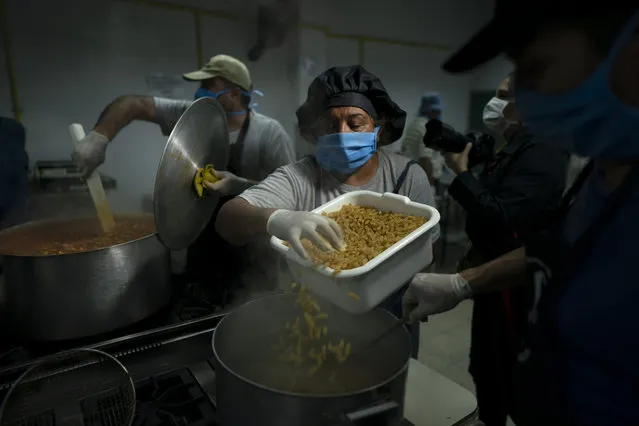 Cooks prepare pasta at a soup kitchen at the San Cayetano church in Jose Leon Suarez neighborhood on the outskirts of Buenos Aires, Argentina, Tuesday, March 31, 2020. The Argentine government said Tuesday that the number of people requesting food assistance has increased following the lockdowns that have left many people unable to work amid the COVID-19 pandemic. (Photo by Victor R. Caivano/AP Photo)