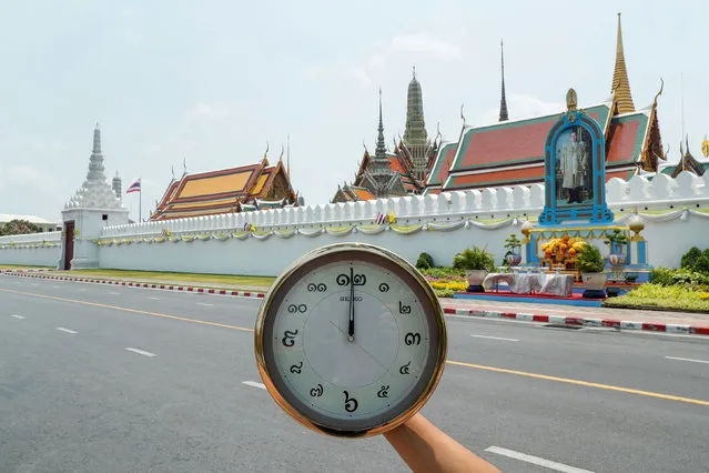 A clock showing the time at noon, is displayed for a photo as Wat Phra Si Rattana Satsadaram (The Temple of the Emerald Buddha, also known as The Grand Palace), is closed for visitors due to the coronavirus disease (COVID-19) outbreak, stands next to an empty road in Bangkok, Thailand, March 31, 2020. (Photo by Jorge Silva/Reuters)