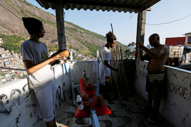 Manoel Pereira Costa (R), known as “Master Manel”, prepares cabacas, to be used with the musical instrument berimbau, with two of his students at his home in the Rocinha favela in Rio de Janeiro, Brazil, July 24, 2016. (Photo by Bruno Kelly/Reuters)
