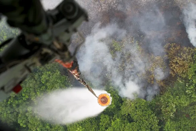 A helicopter drops water to extinguish a fire at a plantation in Kubu Raya district, Indonesia's West Kalimantan province September 3, 2015  in this photo taken by Antara Foto. (Photo by Yohanes Kurnia Irawan/Reuters/Antara Foto)