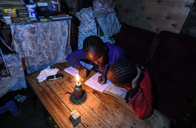 Slum dwellers study by candlelight at their makeshift tents in Mathare, the second informal settlements in Kenya, Nairobi on January 15, 2025. In Kenya, an East African nation, over half the population resides in makeshift shelters. In Nairobi, the country's capital, the Mathare slum houses hundreds of thousands of people. Many children are forced to study at home due to financial challenges, including inadequate schools, poor infrastructure, and a lack of educational supplies. Without access to electricity or proper lighting, residents endure evenings in dimly lit tin homes. Despite these harsh conditions, children in Mathare strive to continue their education, often studying by candlelight. (Photo by Gerald Anderson/Anadolu via Getty Images)