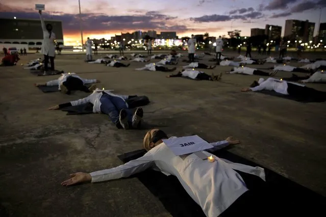 Nurses lay on the ground to represent colleagues who died in their fight against the new coronavirus pandemic, during a protest marking International Nurses Day, in Brasilia, Brazil, Tuesday, May 12, 2020. (Photo by Eraldo Peres/AP Photo)