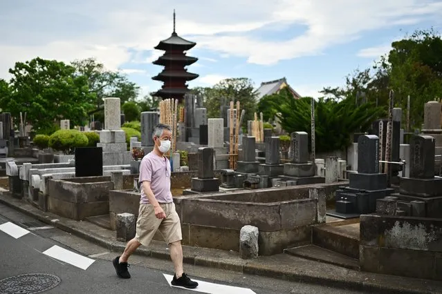 A man wearing a face mask walks in a cemetery near the Honmonji Goju-no-to Pagoda amid the COVID-19 coronavirus outbreak in Tokyo on May 10, 2020. (Photo by Charly Triballeau/AFP Photo)