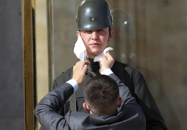 A man wipes the face of a Turkish soldier wearing a face mask for protection against the new coronavirus, before a ceremony at the mausoleum of Mustafa Kemal Ataturk, the founder of modern Turkey, in Ankara, Turkey, Tuesday, May 19, 2020. This year's limited ceremony is marking the 101st anniversary of the start of Turkey's War of Independence under the leadership of the young Ottoman army general. (Photo by Burhan Ozbilici/AP Photo)