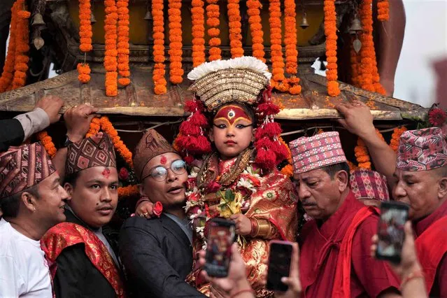 Nepal's revered living goddess Kumari is carried to be taken around in a wooden chariot during the annual Indra Jatra festival in Kathmandu, Nepal, Friday, September 9, 2022. The living goddess was pulled around the main parts of the capital Friday by devotees on a wooden chariot as tens of thousands of people lined up the old city to get a glimpse and be blessed. (Photo by Niranjan Shrestha/AP Photo)
