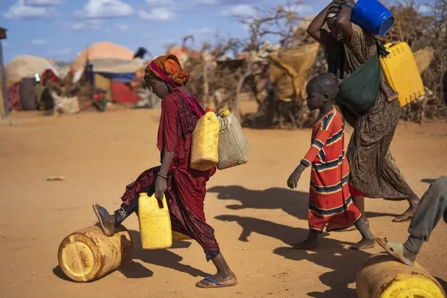 A Somali woman and children carry water at a camp for displaced people on the outskirts of Dollow, Somalia on Tuesday, September 20, 2022. (Photo by Jerome Delay/AP Photo)