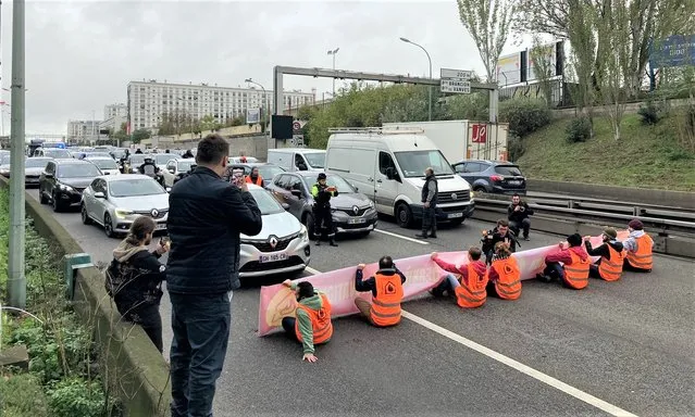 Environmental activists from the Derniere Renovation group hold a banner while sitting to block traffic on a southern part of the Parisian peripheral road, on November 7, 2022. (Photo by Aurore Mesenge/AFP Photo)