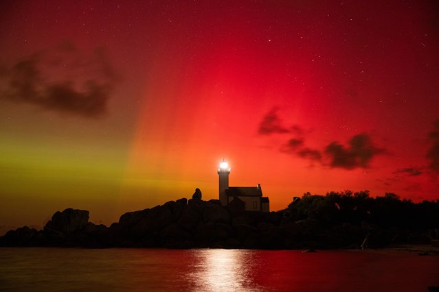 An aurora borealis tints the sky red and green above the Pontusval lighthouse in Brignogan, North Finistere, France, on October 10 2024. (Photo by Vincent Feuray/Hans Lucas via AFP Photo)