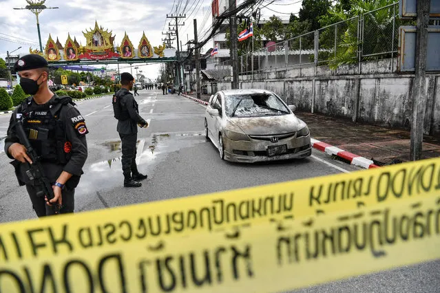 Police officials stand near a partly damaged car, after a car bomb exploded outside a police accommodation in Narathiwat town, southern Thailand, on November 22, 2022. One person died and more than two dozen were injured in the attack, the provincial governor said. (Photo by Madaree Tholala/AFP Photo)