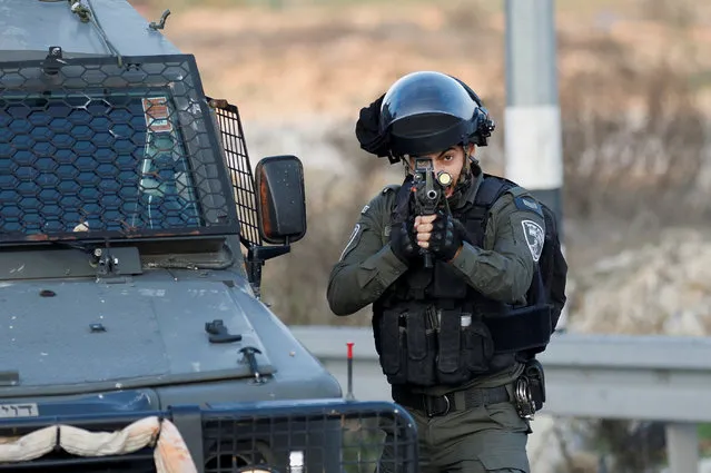 A member of the Israeli border police points his weapon during a clash with Palestinians at Beit El, near Ramallah, in the Israeli-occupied West Bank on December 8, 2022. (Photo by Mohamad Torokman/Reuters)