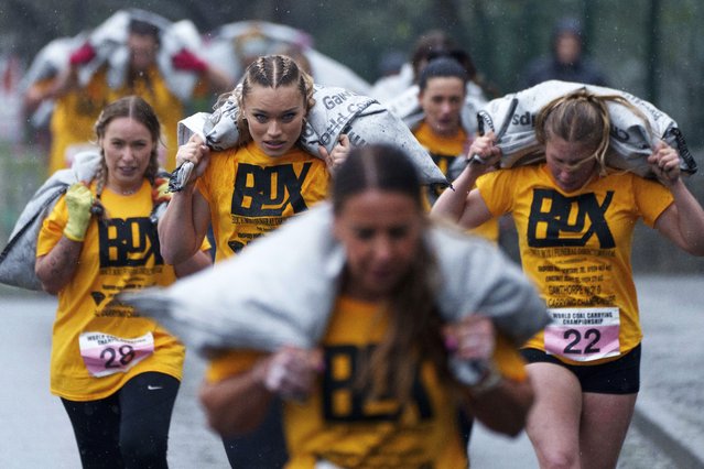 Women's race competitors, including Jodie Ounsley, center, who plays Fury in the British TV show “Gladiators”, run with a 20kg sack of coal over a 1.1km course during the World Coal Carrying Championships in Ossett, West Yorkshire, England, Monday, April 21, 2025. (Photo by Jon Super/AP Photo)