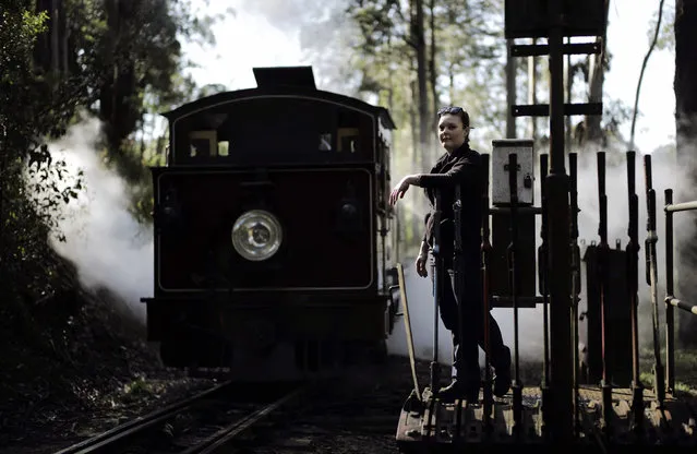 Puffing Billy steam railway guard Emma Pallister leans on the levers used to switch tracks as steam engine 12A passes by at Belgrave station near Melbourne, October 20, 2014. (Photo by Jason Reed/Reuters)