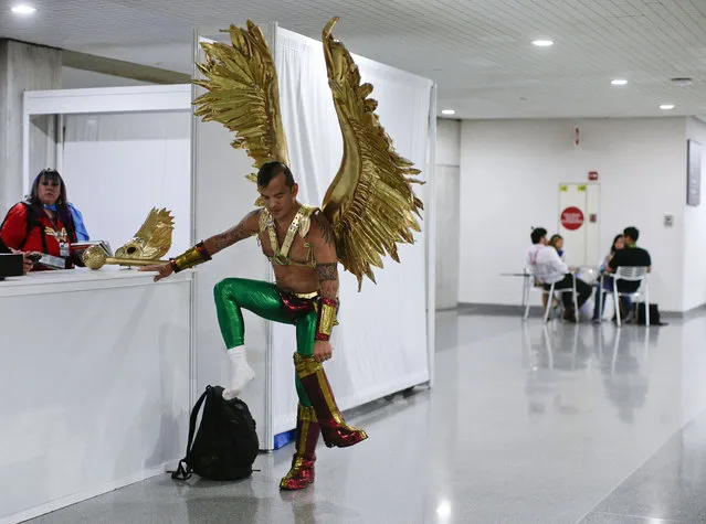 Diego Vargas puts on the boots to his Hawkman costume while attending New York Comic Con, Thursday, October 8, 2015, in New York. The pop culture convention, featuring the latest in comics, graphic novels, anime, manga, video games, toys, movies and television, runs through Sunday. (Photo by Julie Jacobson/AP Photo)