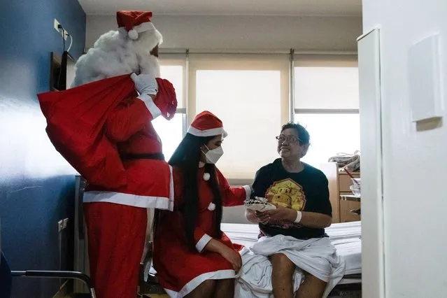 Hospital staff dressed up as Santa Claus greet a patient at a hospital in Pasig City, Metro Manila, on December 25, 2022. (Photo by Kevin Tristan Espiritu/AFP Photo)