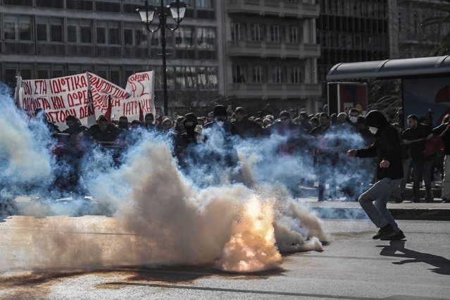 A protester reacts to a tear canister launch during clashes with police at a students' demonstration in front of the Greek Parliament in Athens, on March 8, 2024. Thousands of students from across Greece protested in Athens on March 8, hours before parliament was set to approve a disputed law on private universities which they say will create a two-tier favouring the rich. (Photo by Aris Messinis/AFP Photo)