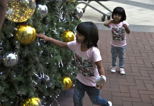 Children play with decorations on a Christmas tree at the entrance to the Rosebank Shopping Mall in Johannesburg Saturday, December 23, 2022. South Africa's Christmas 2022 is a start/stop affair because the country's daily power cuts are hitting just about every aspect of the holiday with businesses and families coping with rolling outages of electricity lasting from seven to 10 hours per day. (Photo by Denis Farrell/AP Photo)
