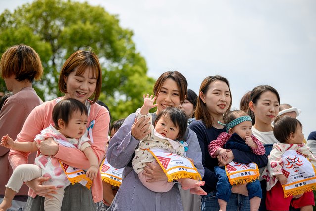 Parents hold their children before the start of their “crying baby sumo” match at the Sensoji temple in Tokyo on April 26, 2025. (Photo by Philip Fong/AFP Photo)