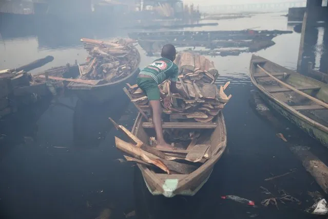 A boy loads a canoe with firewood at Okobaba sawmill at the edge of the Lagos Lagoon June 24, 2014. (Photo by Akintunde Akinleye/Reuters)