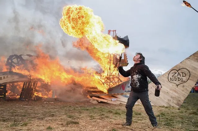 A fire-eater performs after opponents to the former Notre-Dame-des-Landes (NDDL) airport project, symbolically burned a makeshift model of the airport during a rally to celebrate the government's decision to stop the construction of the airport at the ZAD (“zone a defendre”, zone to defend) in Notre-Dame-des-Landes, north of Nantes, western France, on February 10, 2018. Thousands of opponents of the former Notre-Dame-des-Landes airport project are expected to celebrate on February 10 the “historic victory” obtained after 50 years of protest and to reaffirm their determination to win a second battle, that of the collective management of land “saved from concrete”. (Photo by Jean-Sebastien Evrard/AFP Photo)