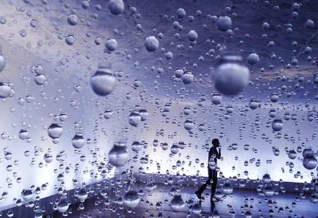 A man walks among lightbulbs filled with water as part of the exhibition “Lagrimas de Sao Pedro” (Tears of Saint Peter) by Brazilian artist Vinicius Silva, at a cultural center in Rio de Janeiro, March 21, 2013. The artist used six thousand lightbulbs to create the idea of rain, showing the relationship between peasants and rain after singing and praying for Saint Peter to cry. International Water Day is held on March 22. (Photo by Pilar Olivares/Reuters)