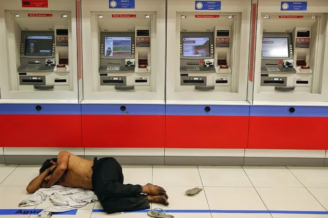 A man sleeps in front of ATM machines on Paulista Avenue in central Sao Paulo, in this June 8, 2014 file photo. (Photo by Damir Sagolj/Reuters)