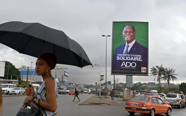A resident walks past Ivory Coast's incumbent President Alassane Ouattara's campaign poster in street in Abidjan on October 15, 2020, on the first day of his presidential campaign ahead of the October 31, 2020 presidential elections. (Photo by Issouf Sanogo/AFP Photo)