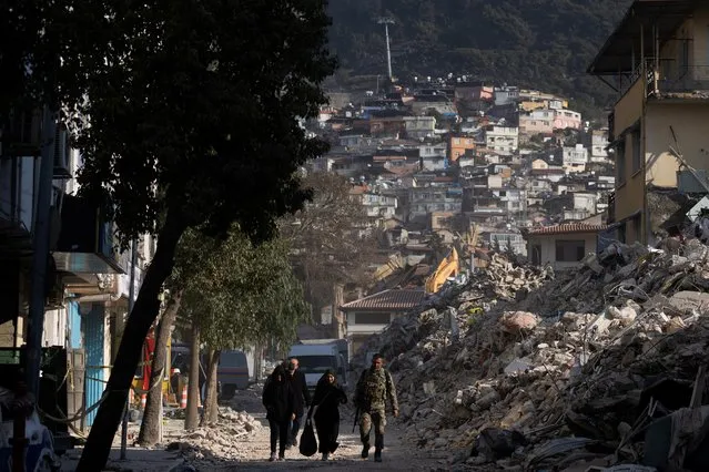 Turkish serviceman walks along a street with two women in the aftermath of a deadly earthquake in Antakya, Turkey on February 16, 2023. (Photo by Maxim Shemetov/Reuters)