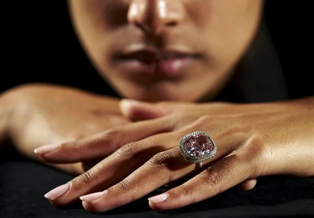 An employee poses with a cushion-shaped 16.08 carat vivid pink diamond at Christie's auction house in Geneva, Switzerland October 30, 2015. The diamond is estimated to sell for $23-28 million when auctioned during the Magnificent Jewels auction in Geneva on November 10. The stone is set as a ring, that includes a double row of pave-set white diamonds that border and accentuate the main stone, along with a third row of small pink diamonds beneath. (Photo by Denis Balibouse/Reuters)