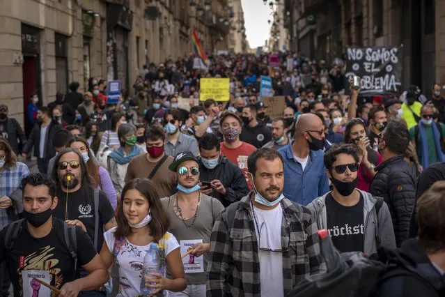 Workers of several sectors including restaurants, bars, hotel, taxi, and nightclubs march during a protest against the latest virus restrictions in Barcelona, Spain, Wednesday, October 28, 2020. Since Oct. 14 bars and restaurants have been closed, allowed to serve food and drink for take-away and delivery only. On Sunday a curfew from 10p.m. to 6 a.m. was imposed. Still, virus cases are surging and Catalan authorities are now considering even more restrictions including weekend lockdowns. Banner reads in Spanish “we want to work”. (Photo by Emilio Morenatti/AP Photo)