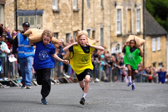 Ben Jones, 10, center, races with a woolsack on his shoulders during the annual Tetbury Woolsack Races in Tetbury, Gloucestershire, England, Monday, May 27, 2024. The Woolsack Races takes place annually in the Wiltshire wool-town of Tetbury. Every year teams of men, women and children carry sacks of British wool, 60-pound (27 kg) for men's races and 35 pounds (16 kg) for women's, up and down the Gumstool Hill with course of 240 yards (220 meters). An official Woolsack Races has been going since 1972, with world records entered in the “Guinness Book of Records”. (Photo by Kin Cheung/AP Photo)