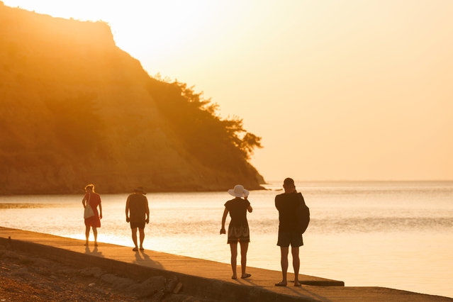 People stroll on the beach during sunset in Agia Triada, in the suburbs of Thessaloniki, Greece, 23 July 2025. High temperatures are forecasted across Greece, with the highest temperatures expected on 24 and 25 July. (Photo by Achilleas Chiras/EPA)