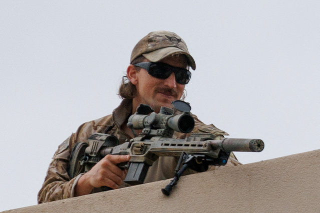 A Special Response Team sniper with a lethal weapon points towards protesters from the roof of the ICE building in Portland, Oregon, U.S., October 4, 2025. (Photo by John Rudoff/Reuters)