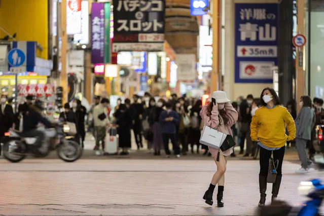 People wearing face masks to help curb the spread of the coronavirus wait to walk across a traffic intersection in Osaka, western Japan, Thursday, November 26, 2020. (Photo by Hiro Komae/AP Photo)