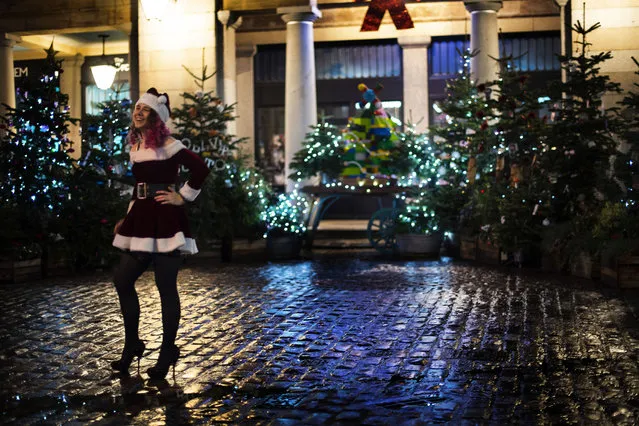 A woman poses in a festive outfit in front of Christmas trees in Covent Garden, London, which has moved into the highest tier of coronavirus restrictions as a result of soaring case rates, Wednesday, December 16, 2020. (Photo by Victoria Jones/PA Wire via AP Photo)