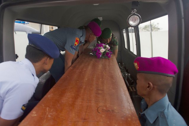 Indonesian military load a casket containing the body of an AirAsia flight QZ8501 passenger recovered off the coast of Borneo into a vehicle at a military base in Surabaya December 31, 2014. (Photo by Sigit Pamungkas/Reuters)