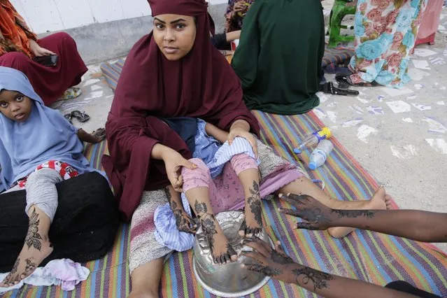 Women and children decorate their hands with henna at a street market as preparations are made for the Muslim holiday of Eid al-Fitr, next Friday, which marks the end of the holy fasting month of Ramadan, in Mogadishu, Somalia, Wednesday, April 19, 2023. (Photo by Farah Abdi Warsameh/AP Photo)