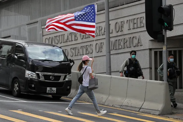 In this July 4, 2020, file photo, a protester carries an American flag during a protest outside the U.S. Consulate in Hong Kong. China says it is imposing restrictions on travel to Hong Kong by some U.S. officials and others in retaliation for similar measures imposed on Chinese individuals by Washington. (Photo by Kin Cheung/AP Photo/File)