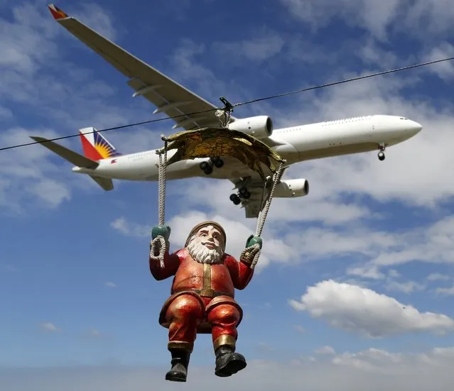 A Philippines Airlines (PAL) plane flies over a Santa Claus doll hanged at a home (unseen) in Manila, Philippines, 07 December 2015. Filipinos celebrate the longest Christmas in the world which starts as early as September every year. (Photo by Francis R. Malasig/EPA)