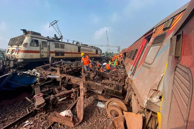A rescue worker sifts through wreckage at the accident site of a three-train collision near Balasore, about 200 km (125 miles) from the state capital Bhubaneswar, on June 3, 2023. At least 233 people were killed and more than 850 more were injured in a horrific three-train collision in India, officials said on June 3, the country's deadliest rail accident in more than 20 years. (Photo by Dibyangshu Sarkar/AFP Photo)