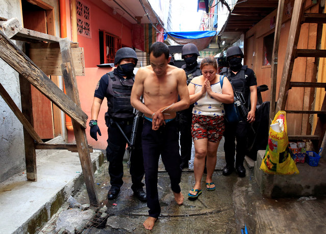 Members of the Philippine National Police (PNP) Special Weapons and Tactics escort a man who was detained for further questioning, following an identity check during the anti-drugs operations in metro Manila, Philippines November 10, 2016. The woman is the man's wife, and is not involved in the questioning. (Photo by Romeo Ranoco/Reuters)